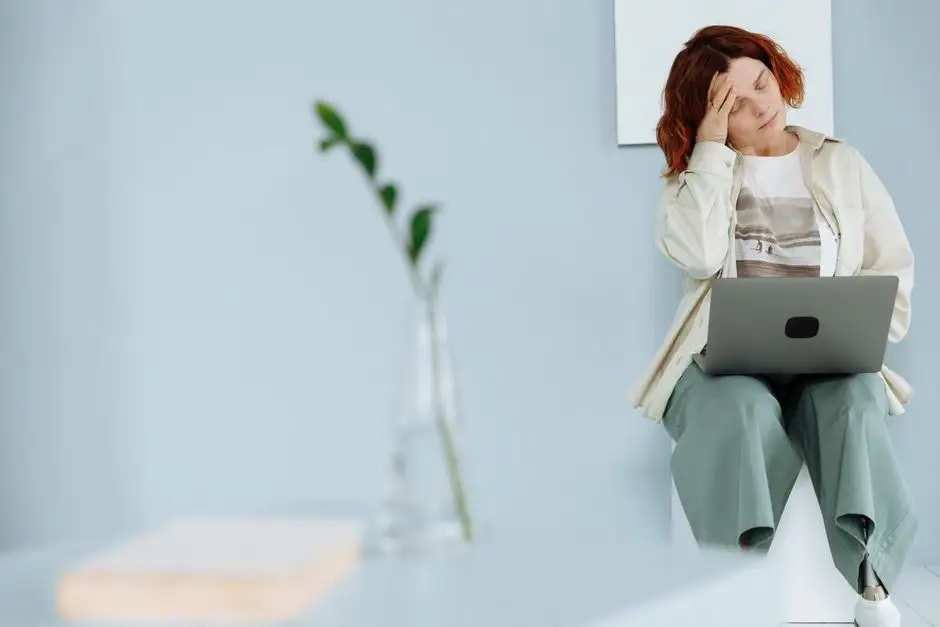 Personne assise tête entre les mains dans un bureau, lumière tamisée, illustration du stress persistant